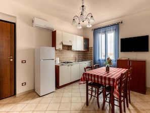 Una cocina compacta equipada con refrigerador, estufa y mesa para cuatro personas.