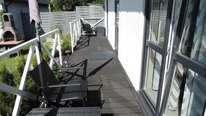 A covered outdoor area with a wooden deck, a grill, and a seating area with chairs. - New Holiday Home for 5 People in Wiselka (gmina Wolin)