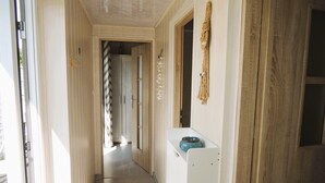 A narrow hallway with a wooden door on the right, a white appliance on the left, and a hanging decoration. - New Holiday Home for 5 People in Wiselka (gmina Wolin)