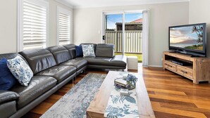 A living room with a leather sofa, a coffee table, and a TV on a wooden stand.
