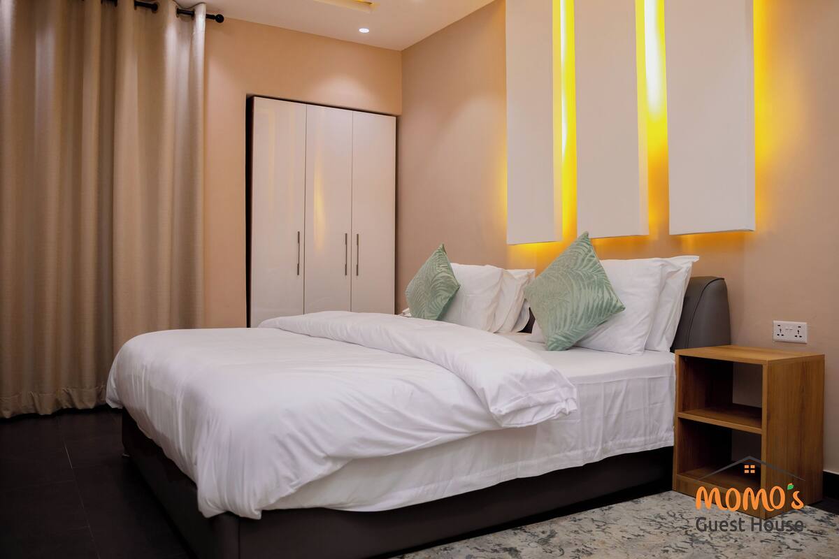 A modern bedroom with a bed, bedside tables, and a wardrobe.