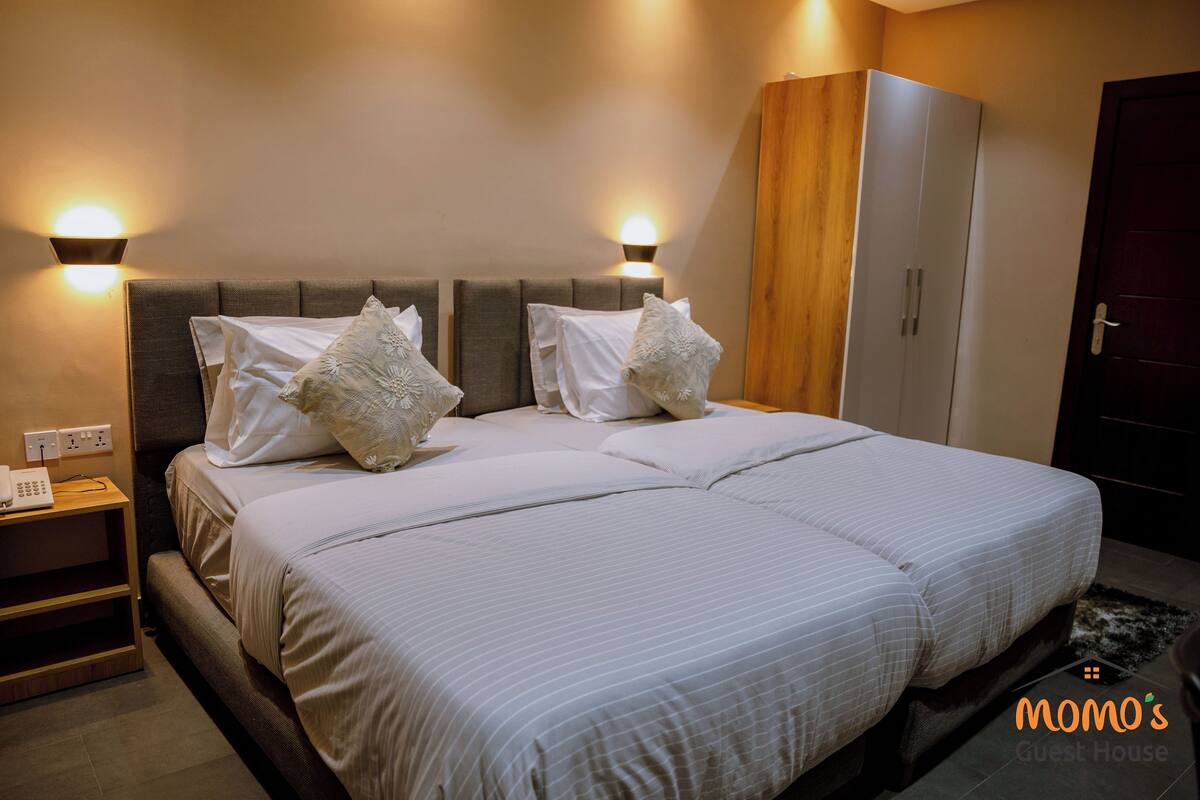 A double bed with a headboard, bedside tables, and wall-mounted lights.