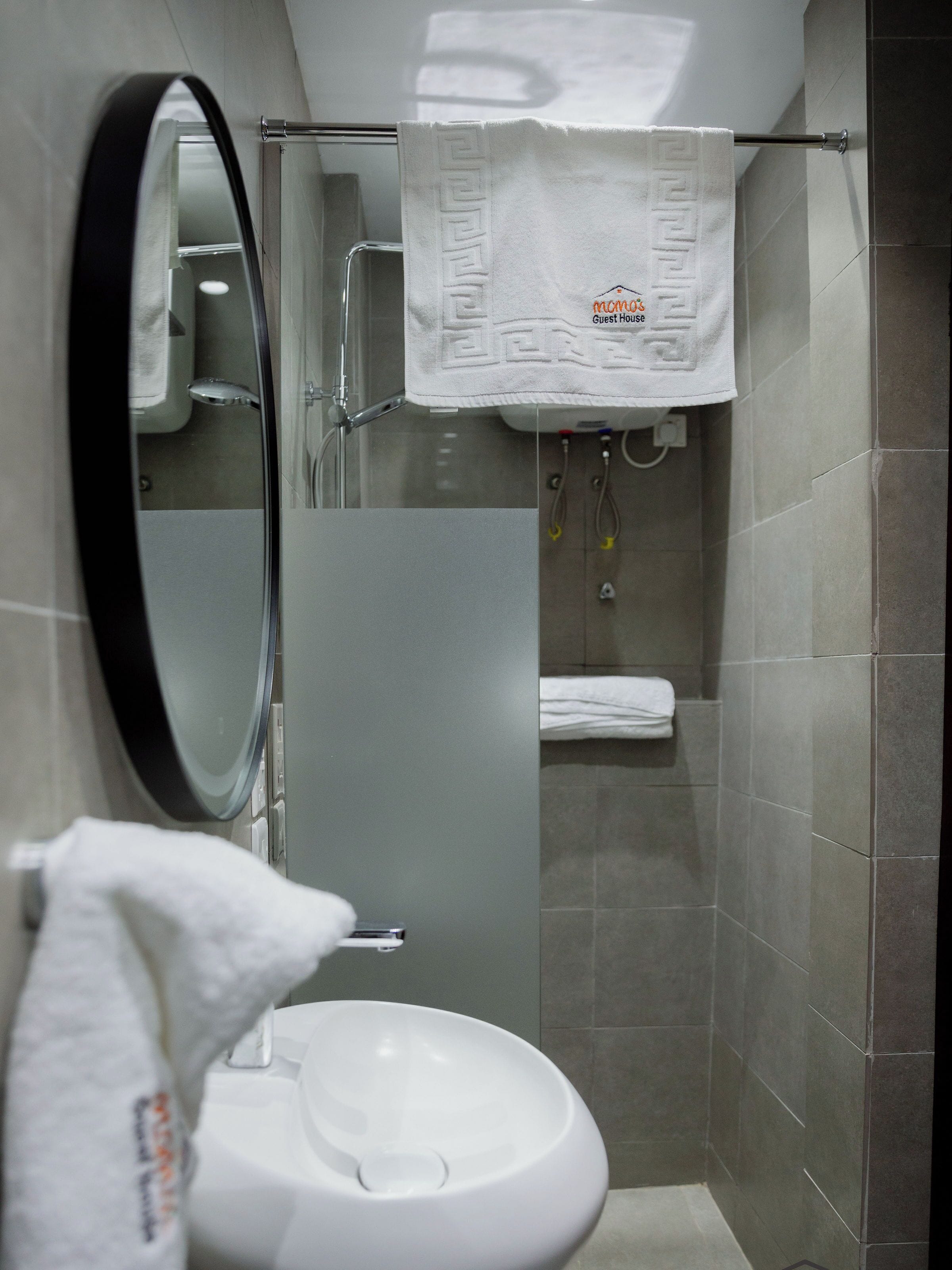 Un baño moderno con inodoro blanco, cabina de ducha de vidrio y toallero con una toalla blanca.