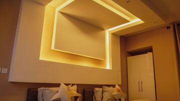 Habitación de hotel con cama, mesita de noche, armario y una lámpara de techo moderna.