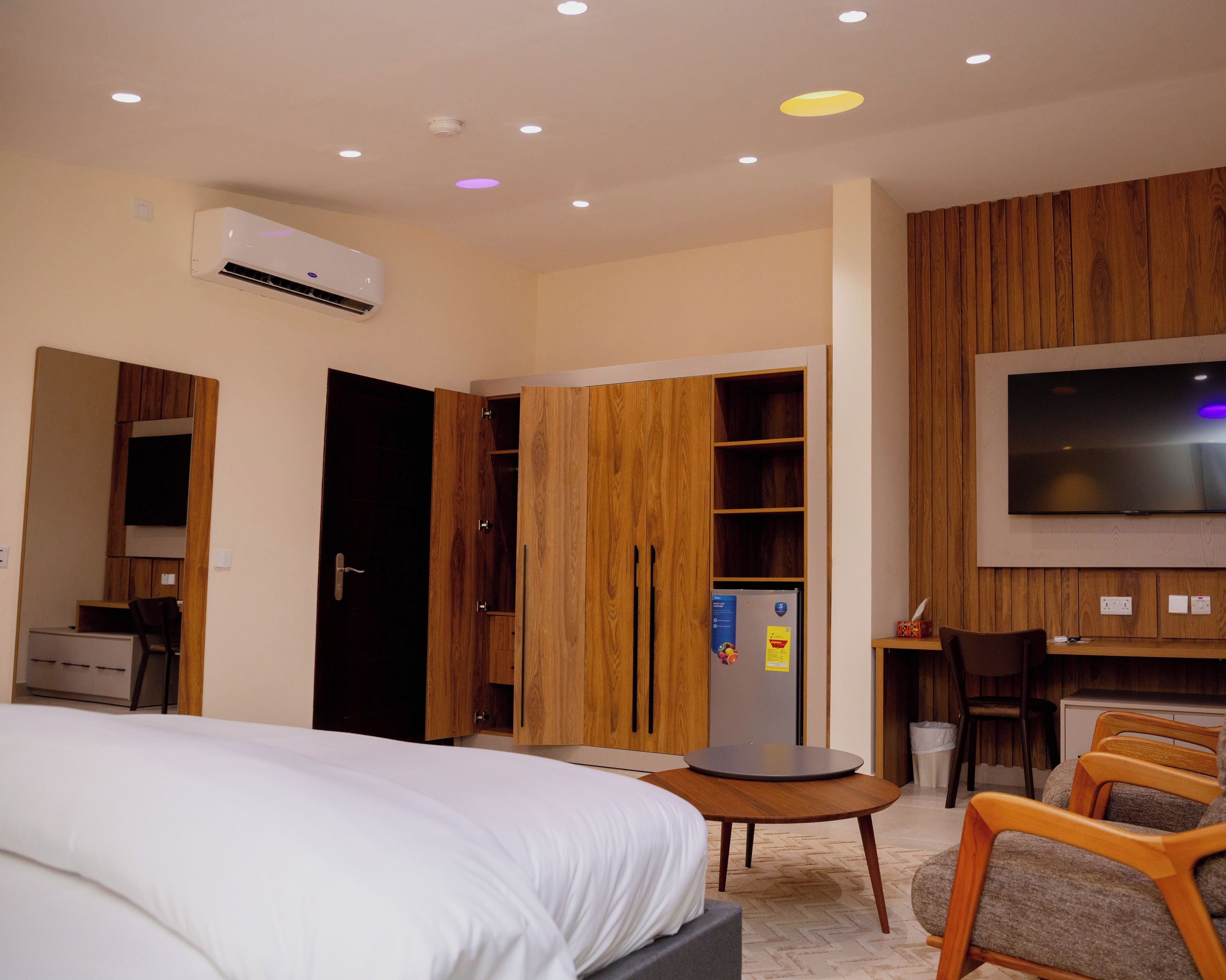 A hotel room with a bed, a desk, a chair, a TV, and a wardrobe.