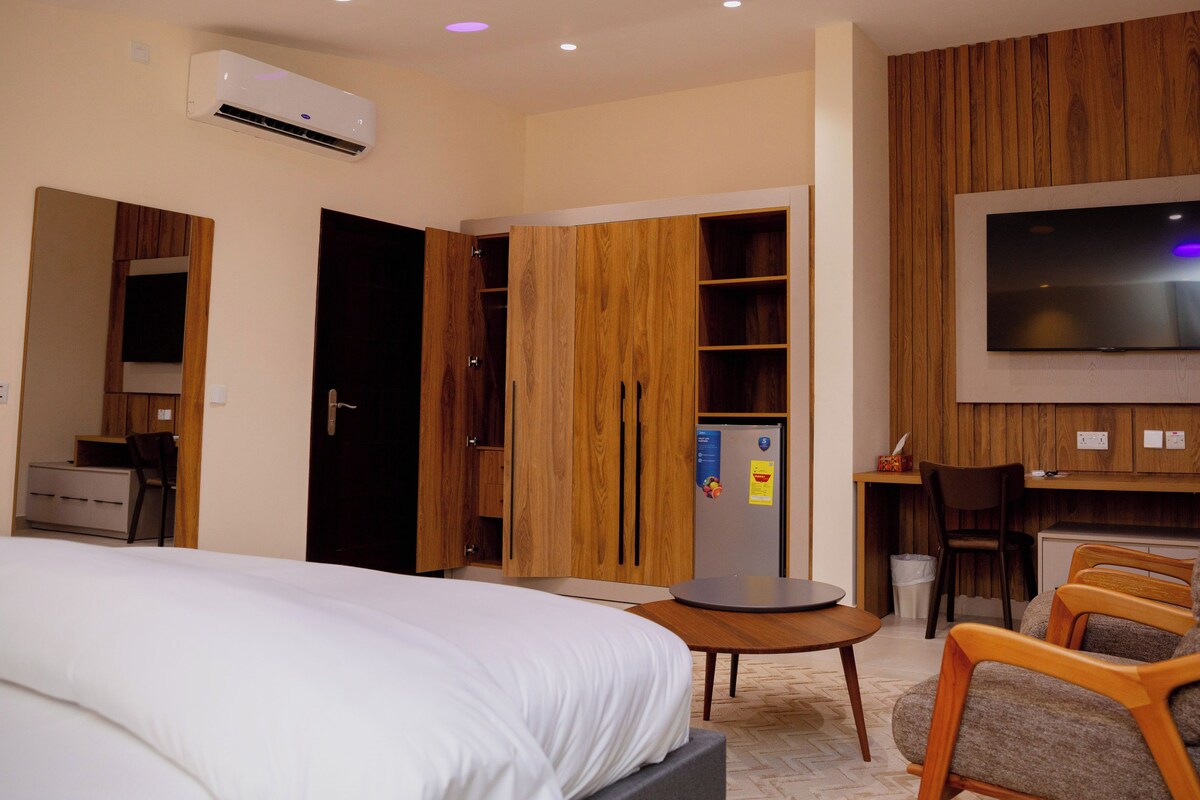 A hotel room with a bed, a desk, a chair, a TV, and a wardrobe.
