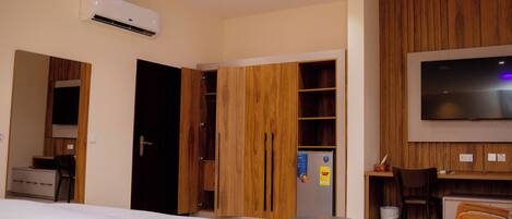 A hotel room with a bed, a desk, a chair, a TV, and a wardrobe.