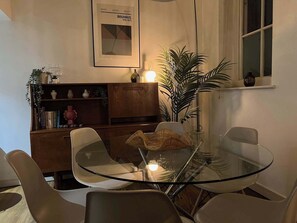 A modern dining area with a glass table and chairs, a wooden bookshelf, and a framed picture on the wall. - Bright and Spacious 3BDR Loft by Tooting Broadway (Greater London)