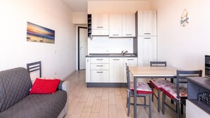 A compact living space with a kitchenette, a dining area, and a sofa with a red pillow. - Apartment in With Swimming Pool and sea View (Castelsardo)