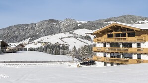 A wooden building with multiple balconies, surrounded by snow-covered mountains and a clear sky. - Alpine Apartment With View & Garden (Wildschönau)