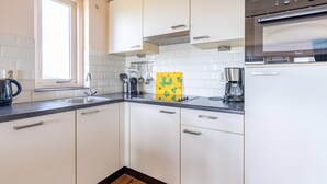 Una cucina moderna con mobili bianchi, un lavello in acciaio inossidabile e un forno integrato.