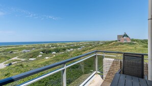 Un balcone con vista su un paesaggio costiero, che include una casa e diversi edifici.