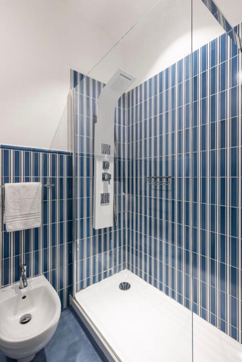 A modern bathroom with a shower, a sink, and a towel rack.