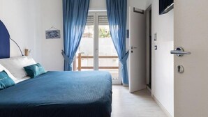 A bedroom with a bed, curtains, a door, and a view through a glass door.