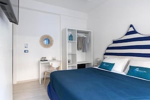Una camera da letto con un letto, un armadio bianco, una scrivania e uno specchio a parete.
