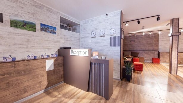 A reception area with a wooden reception desk, a clock, and a wall with framed pictures. - Popock Tsaghkadzor (Tsaghkadzor)