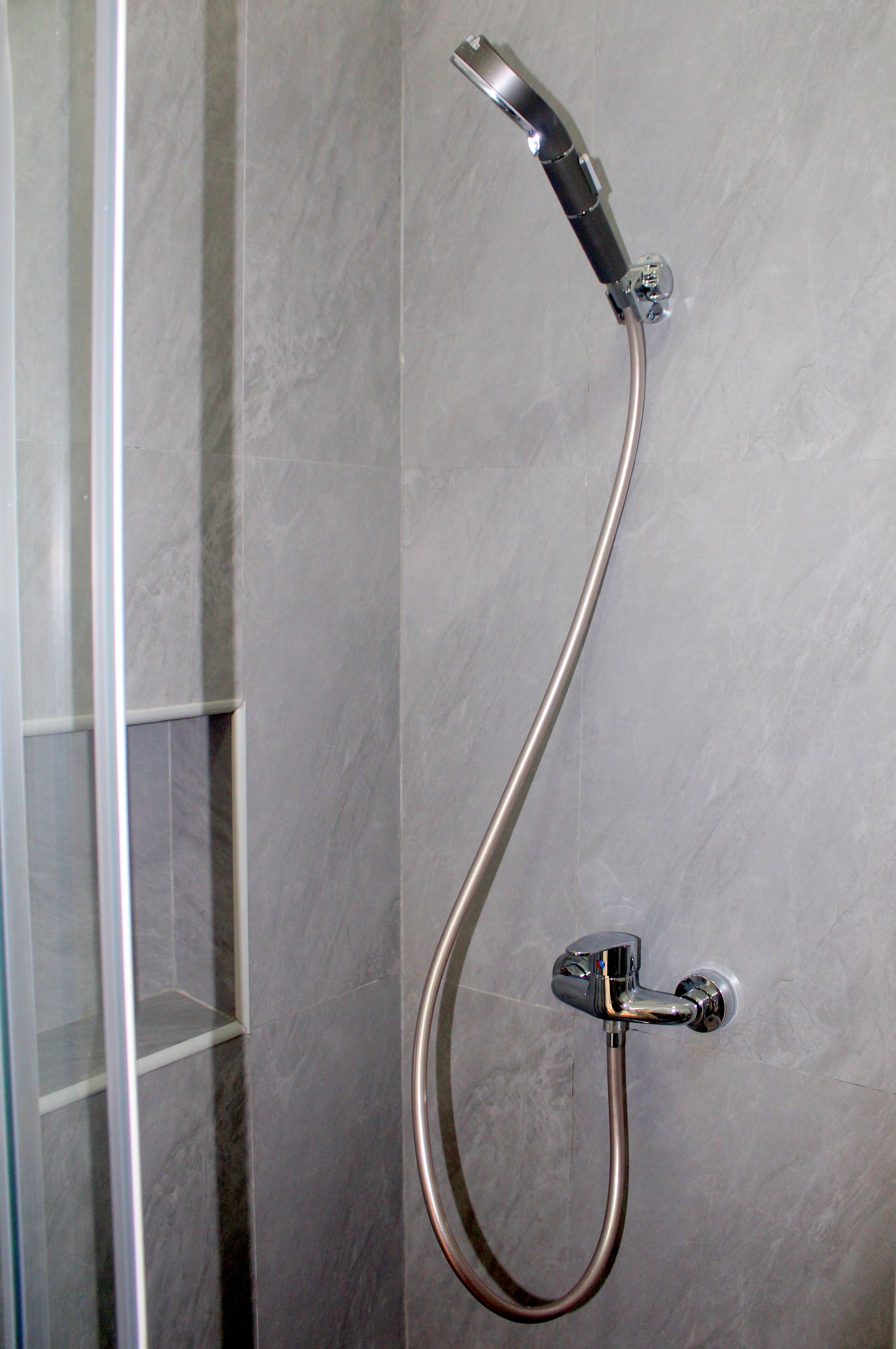 Eine Dusche mit Handbrause und Wandarmatur.