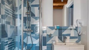 Un baño moderno con cabina de ducha de vidrio, tocador blanco y salpicadero de azulejos geométricos.
