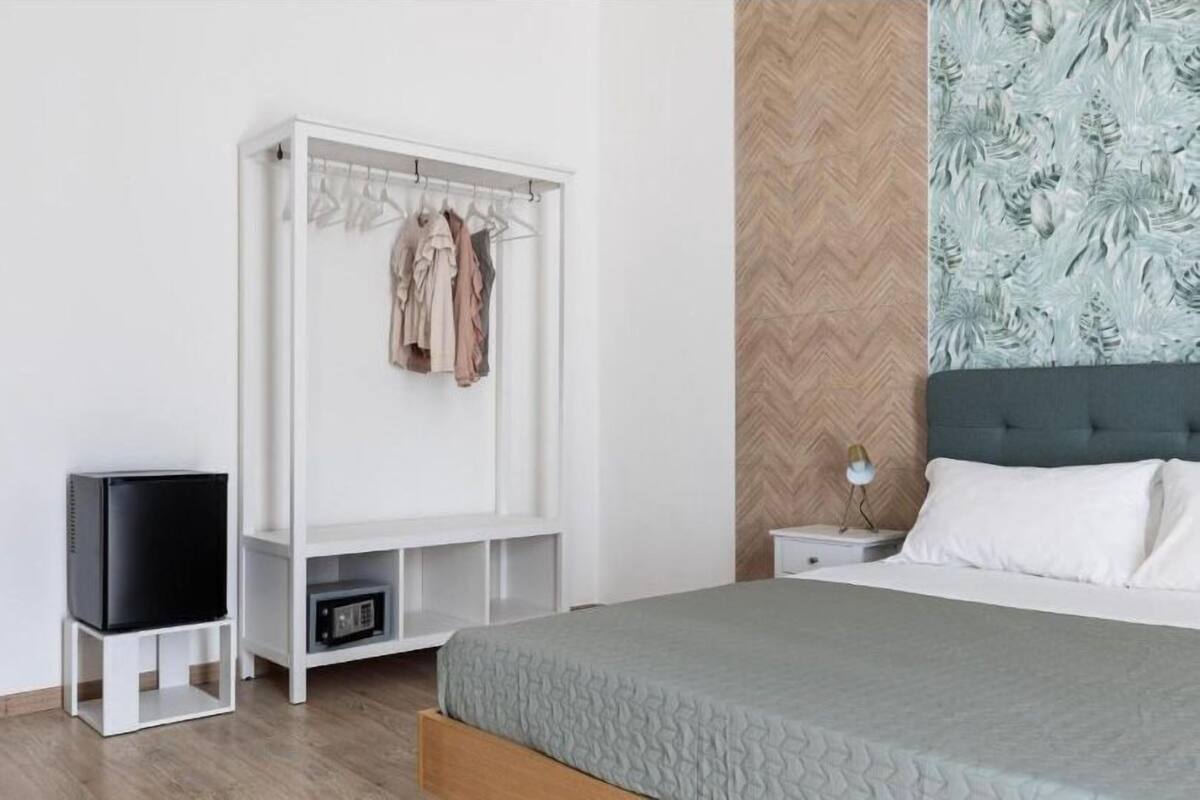 Un dormitorio con cama, armario, televisor y mesita de noche.