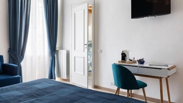 Una habitación de hotel moderna con una cama, un escritorio, una silla y un televisor montado en la pared.