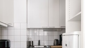 Eine moderne Küche mit weißen Schränken, einer schwarzen Arbeitsplatte und einem weißen Kühlschrank.