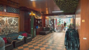 A lobby with a checkered floor, leather sofas, a massage chair, and a reception area with a view of the outside. - Vientiane Ruby Riverside Hotel & Hostel (Vientiane)