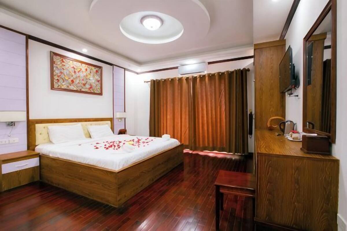Una camera d'albergo con un letto in legno, una scrivania, uno specchio e un grande quadro appeso al muro.