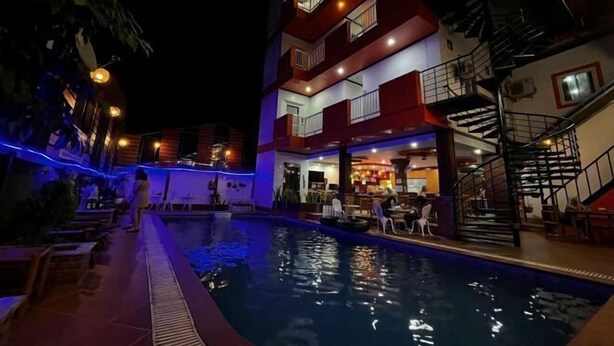 A multi-story hotel with a pool area, outdoor seating, and a bar/lounge area. - Vientiane Ruby Riverside Hotel & Hostel (Vientiane)