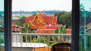 A traditional building with a red roof and golden accents, viewed from a balcony with a table and chair. - Vientiane Ruby Riverside Hotel & Hostel (Vientiane)