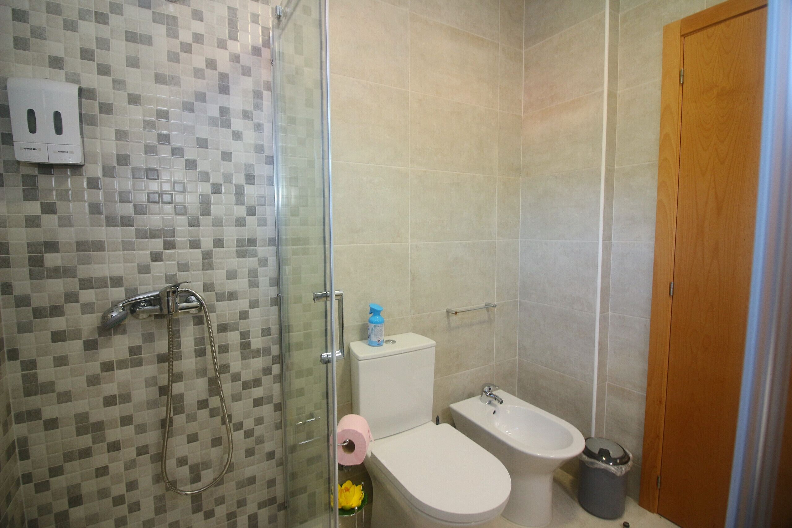 Ein Badezimmer mit Dusche, Toilette, Bidet und Mülleimer.
