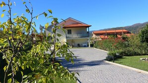 Ein zweistöckiges Gebäude mit rotem Ziegeldach, befestigter Auffahrt und gepflegtem Garten.