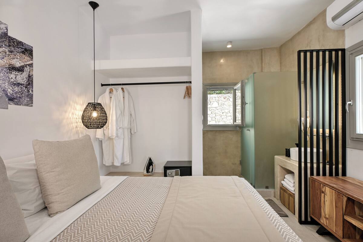 A bedroom with a bed, bedside table, and a hanging light fixture.