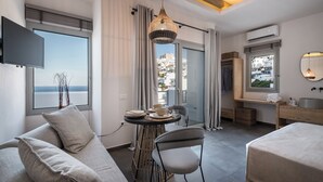 Habitación de hotel moderna con sofá, mesa de comedor y vista a la ciudad.