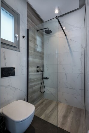 Un baño moderno con ducha de vidrio, inodoro blanco y suelo de madera.