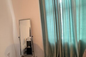 A room with a mirror, a lamp, and a window with curtains. - Beautiful 2BR Apt. With WIFI in a Prime Location (Vienna)