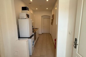 A narrow hallway with a washing machine, a microwave, and a sink. - Beautiful 2BR Apt. With WIFI in a Prime Location (Vienna)