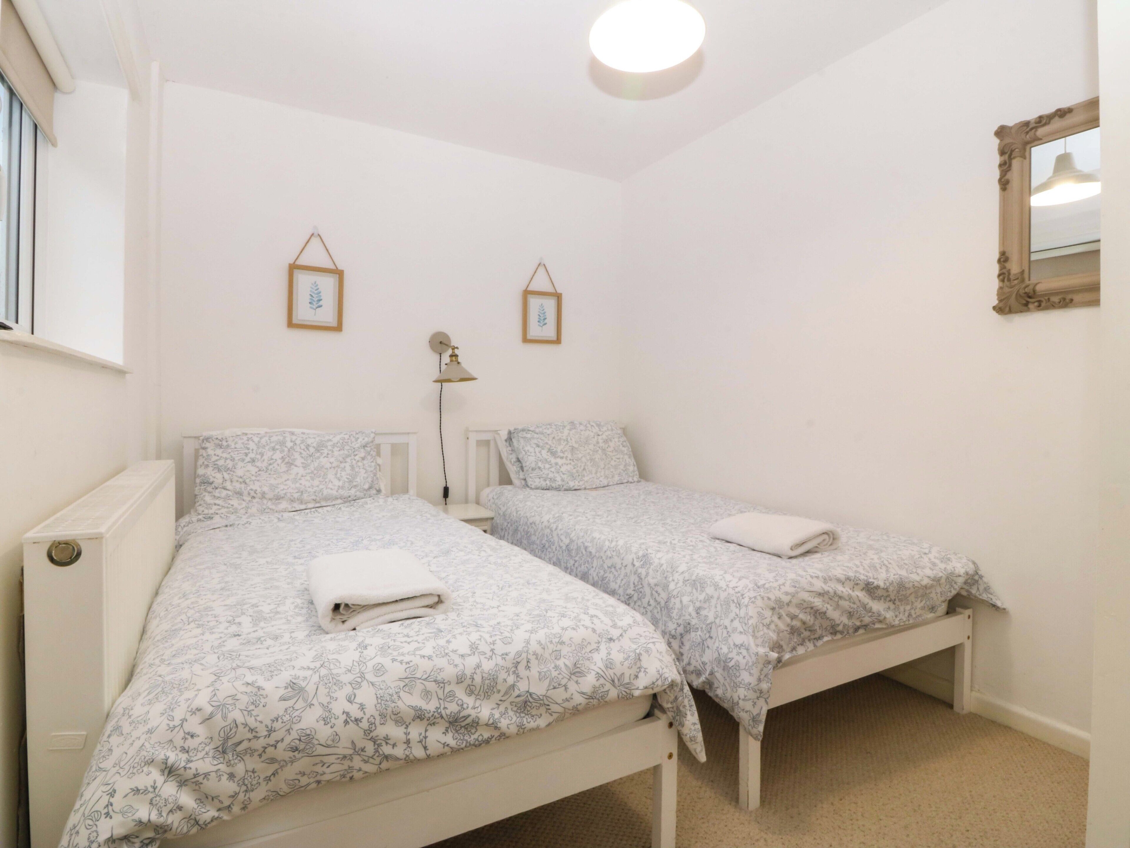 Un dormitorio con dos camas individuales, una lámpara de noche, un radiador y un espejo en la pared.