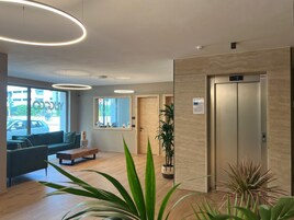 A modern lobby with a sofa, coffee table, and potted plants.