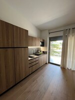 A modern kitchen with wooden cabinets, a sink, and a window with curtains.