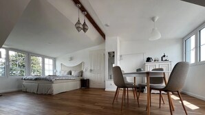 Un espacioso dormitorio tipo loft con una cama grande, un comedor con mesa y sillas, y una zona de cocina.