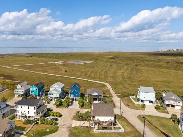 Un quartier résidentiel avec des maisons, un ciel dégagé et une étendue d’eau visible au loin.