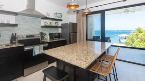 Eine moderne Küche mit Granit-Arbeitsplatten, Edelstahlgeräten und einer großen Kochinsel. Große Fenster bieten Blick auf den Ozean.
