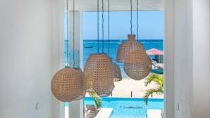 Blick auf ein Schwimmbecken mit Strand und dem Ozean im Hintergrund.