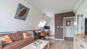 Un salon moderne avec un canapé marron, une table basse en bois et un coin repas comprenant une table et des chaises.