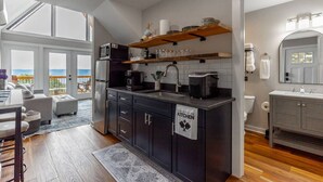 A modern kitchen with dark cabinetry, a built-in oven, and a coffee machine. There is a sign on the door that says "STAY OUT OF THE KITCHEN." - Rally House Pickleball Cabin by Red White & Blue Views (Lookout Mountain)
