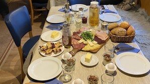Tavolo imbandito con piatti, posate, pane e tagliere di salumi.