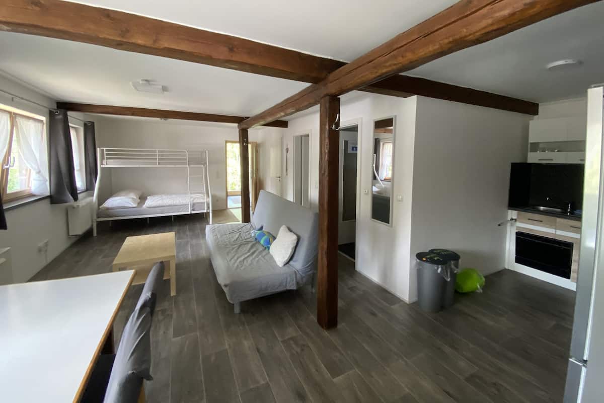Une pièce spacieuse comprenant un lit superposé, un canapé, une table à manger et un coin cuisine.