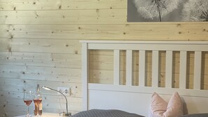 Una camera da letto con una testiera in legno, un comodino con una lampada, due cuscini e una coperta.