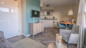 A modern living room with a sofa, a coffee table, a TV, and a dining area with chairs and a table. - Tasteful 2-person Apartment Near the Center of De Koog (De Koog)