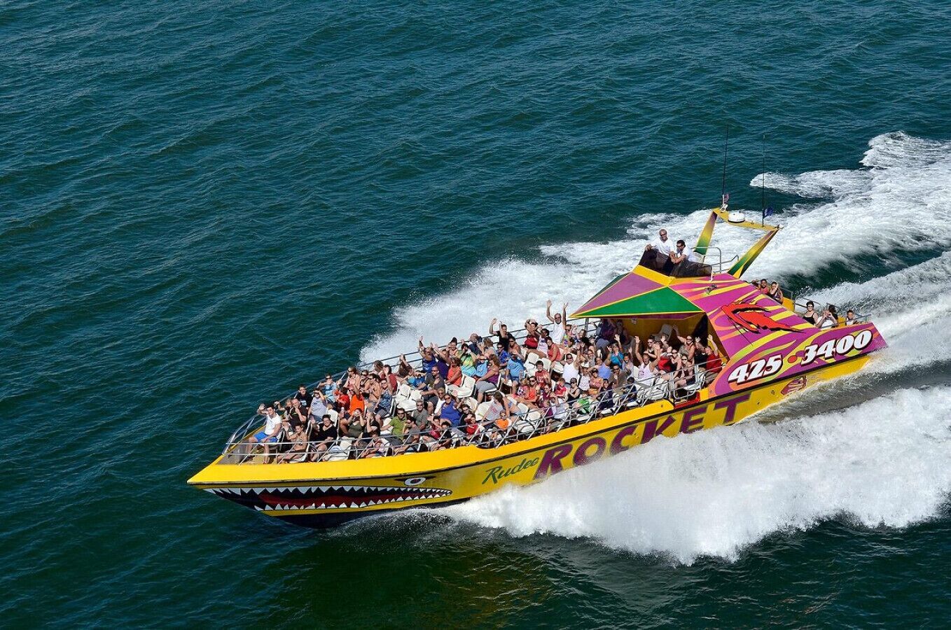 A colorful speedboat with the number 425-3400 and the name 'ROCKET' on its side, filled with passengers enjoying a ride on the water.